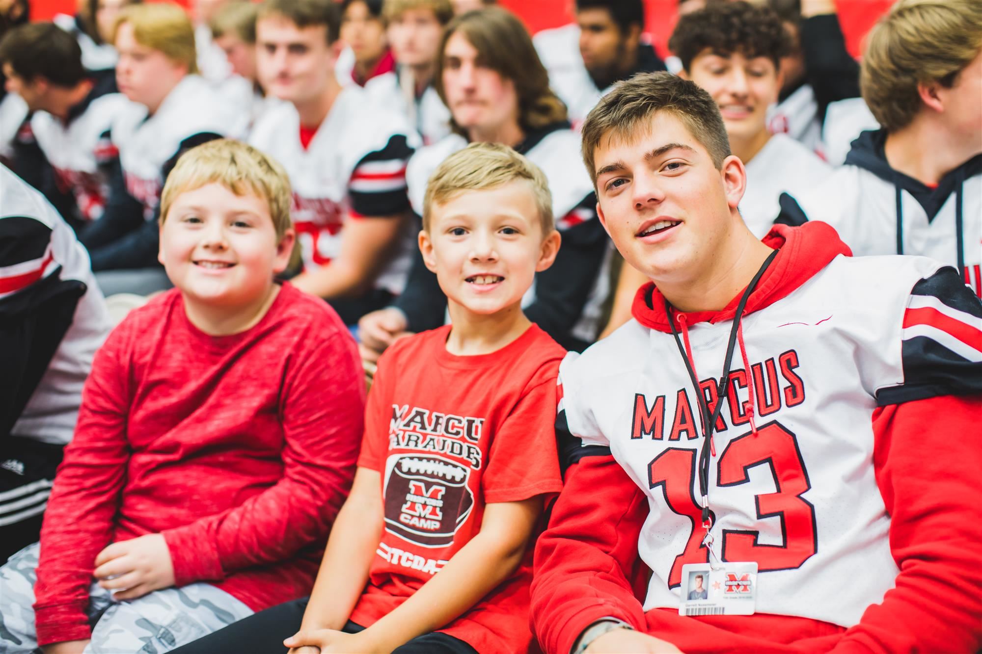 Flower Mound Elementary students sit with MHS football player during the pep rally. 2019 