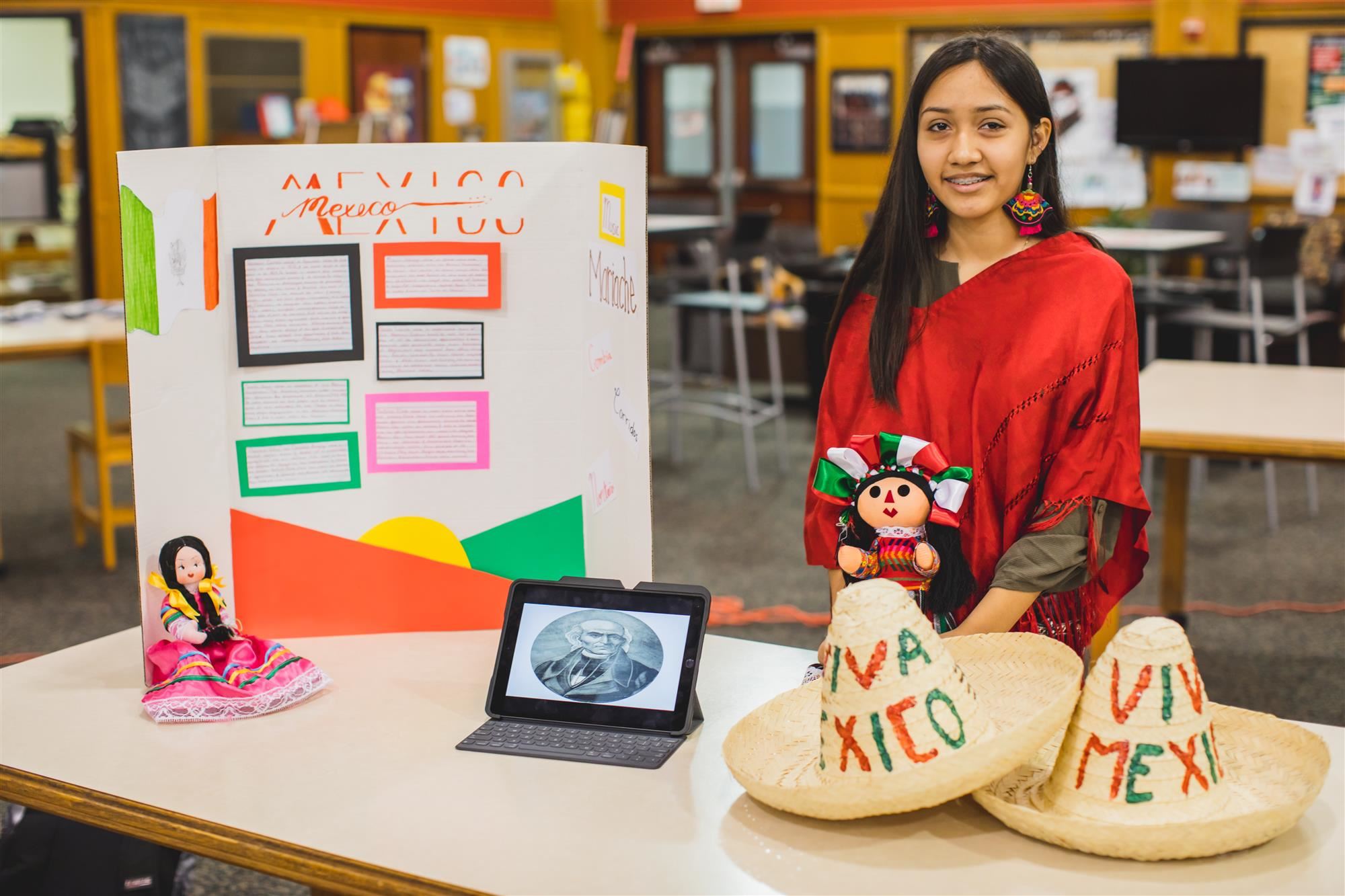 MHS student poses at her booth about Mexico for Celebrate Marcus! 2019 