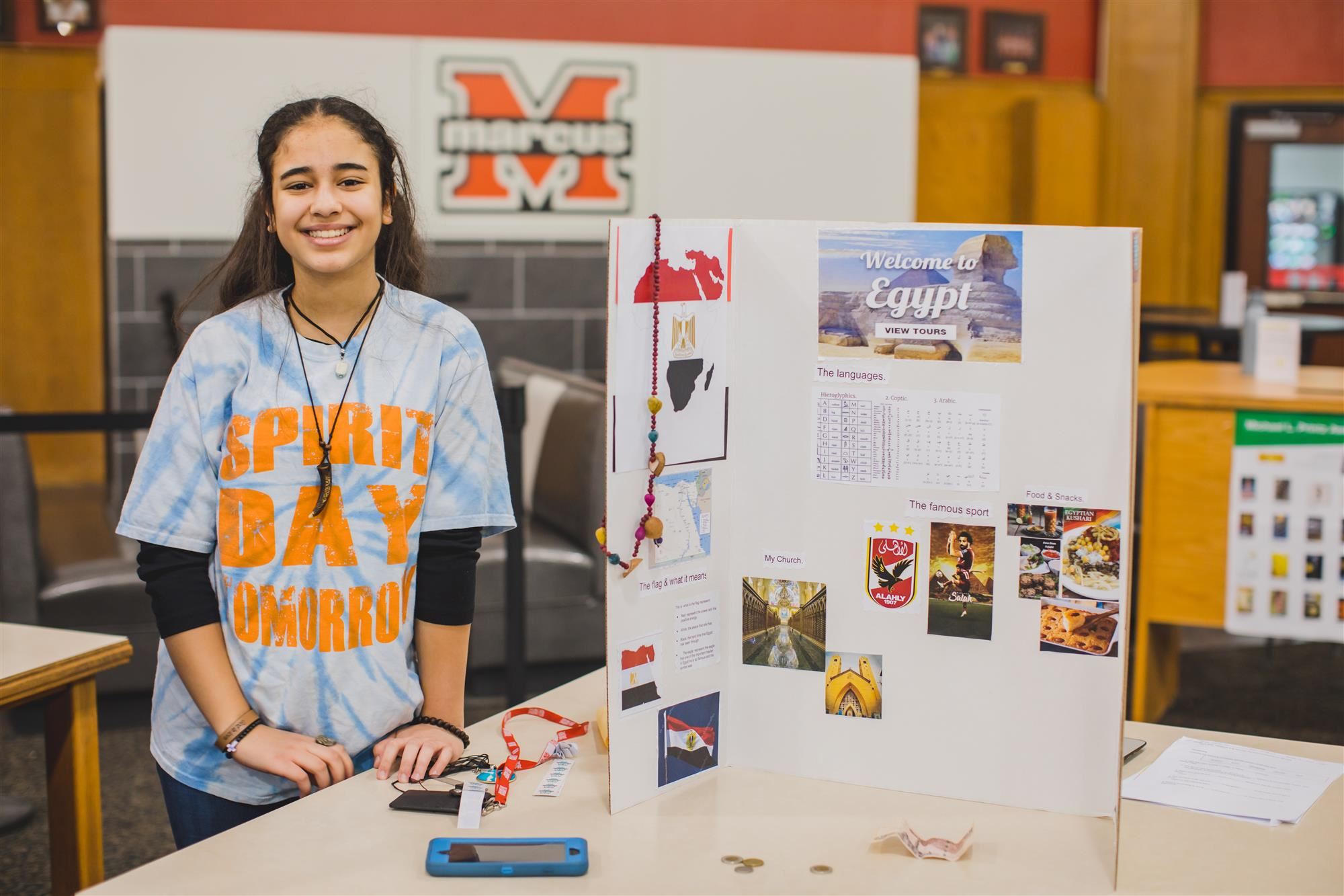 MHS student poses with her poster about Egypt at Celebrate Marcus! 2019 