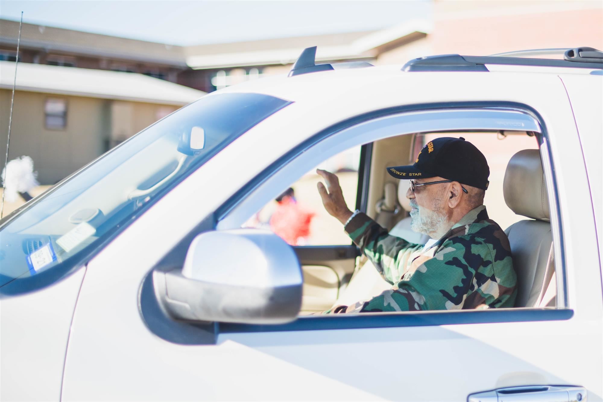 Veterans waves from vehicle during drive-thru parade. 