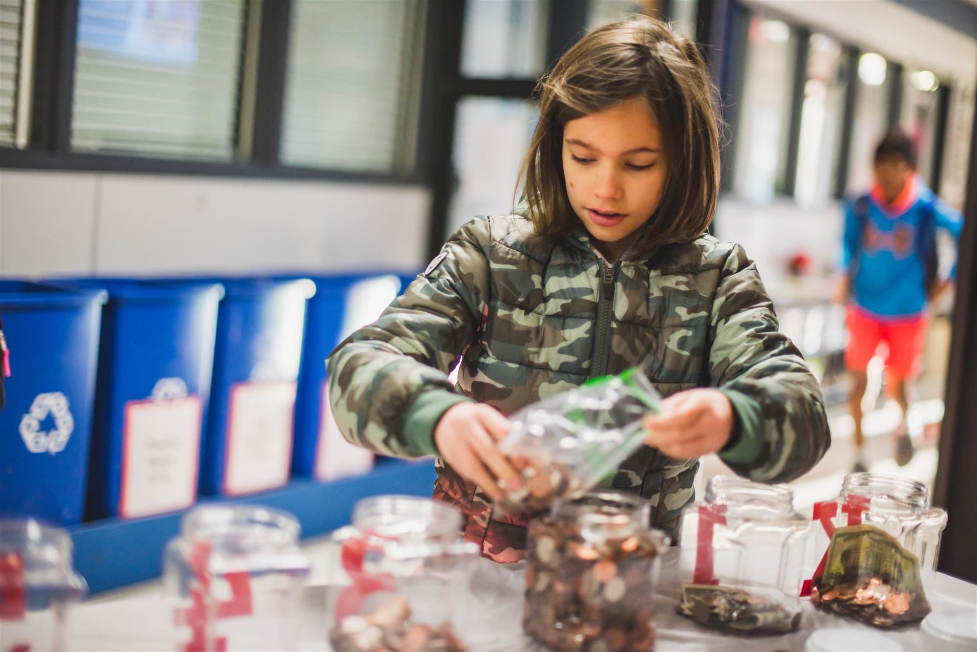 Student adds money into jars 