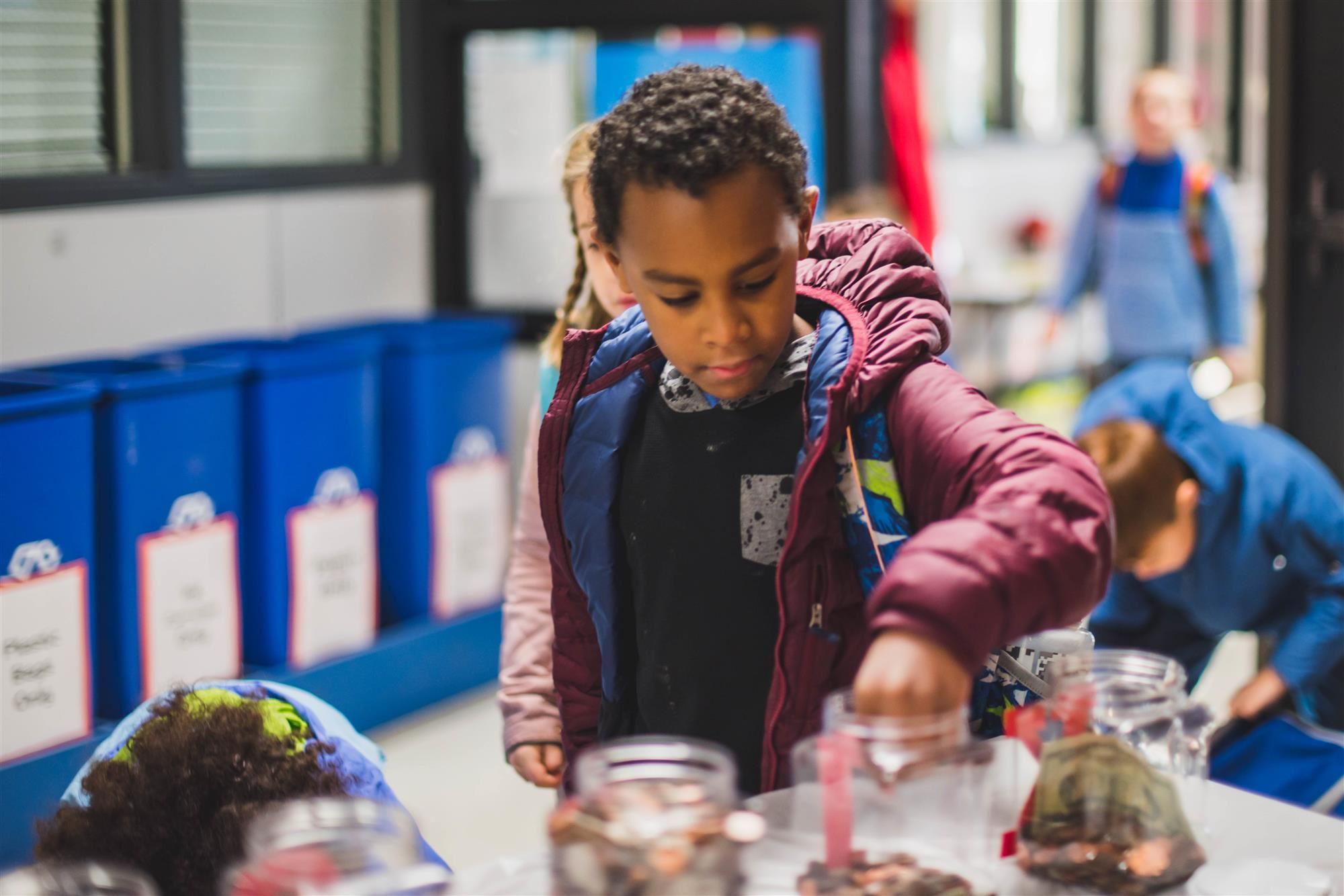 student adds coin to jar 