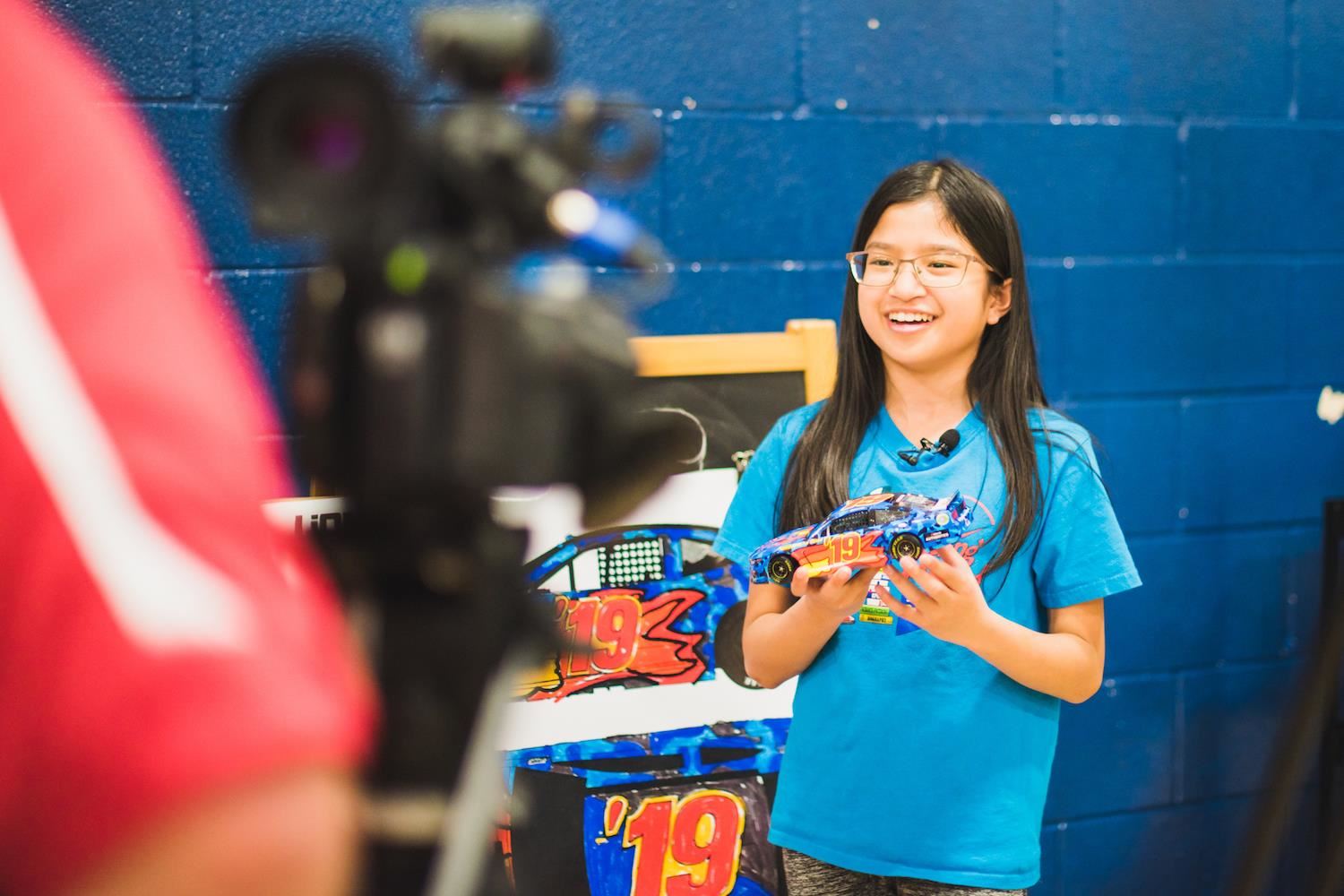 Die-cast winner Ung smiles and speaks to cameras with model car 