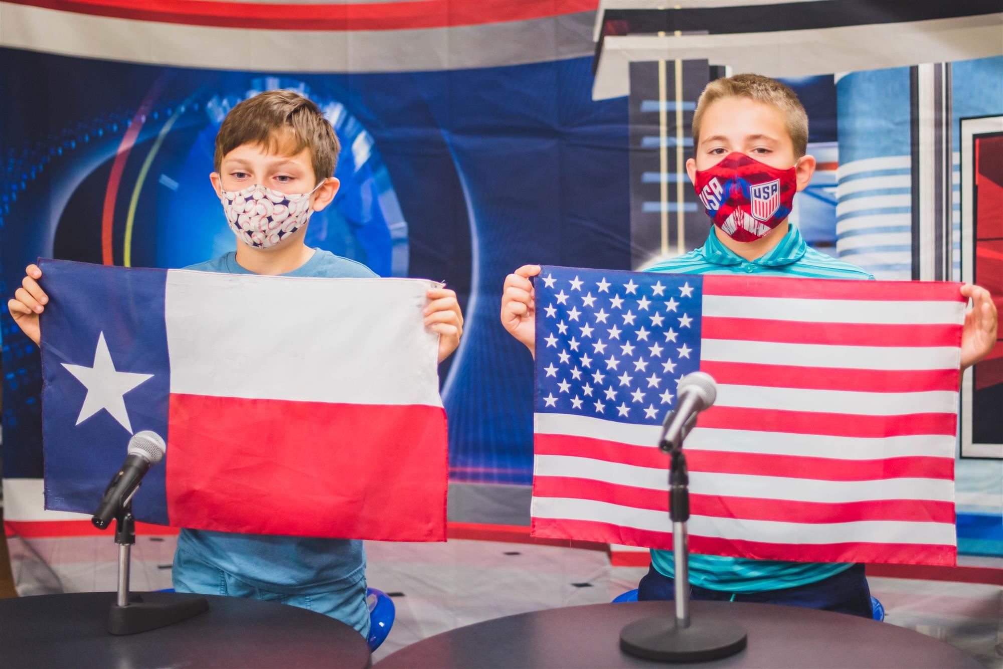 Students hold upp Texas and American flags for morning pledges 