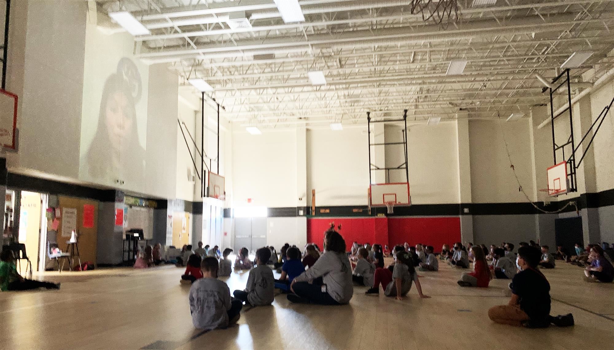 Students watch screen of high school athletes talking 