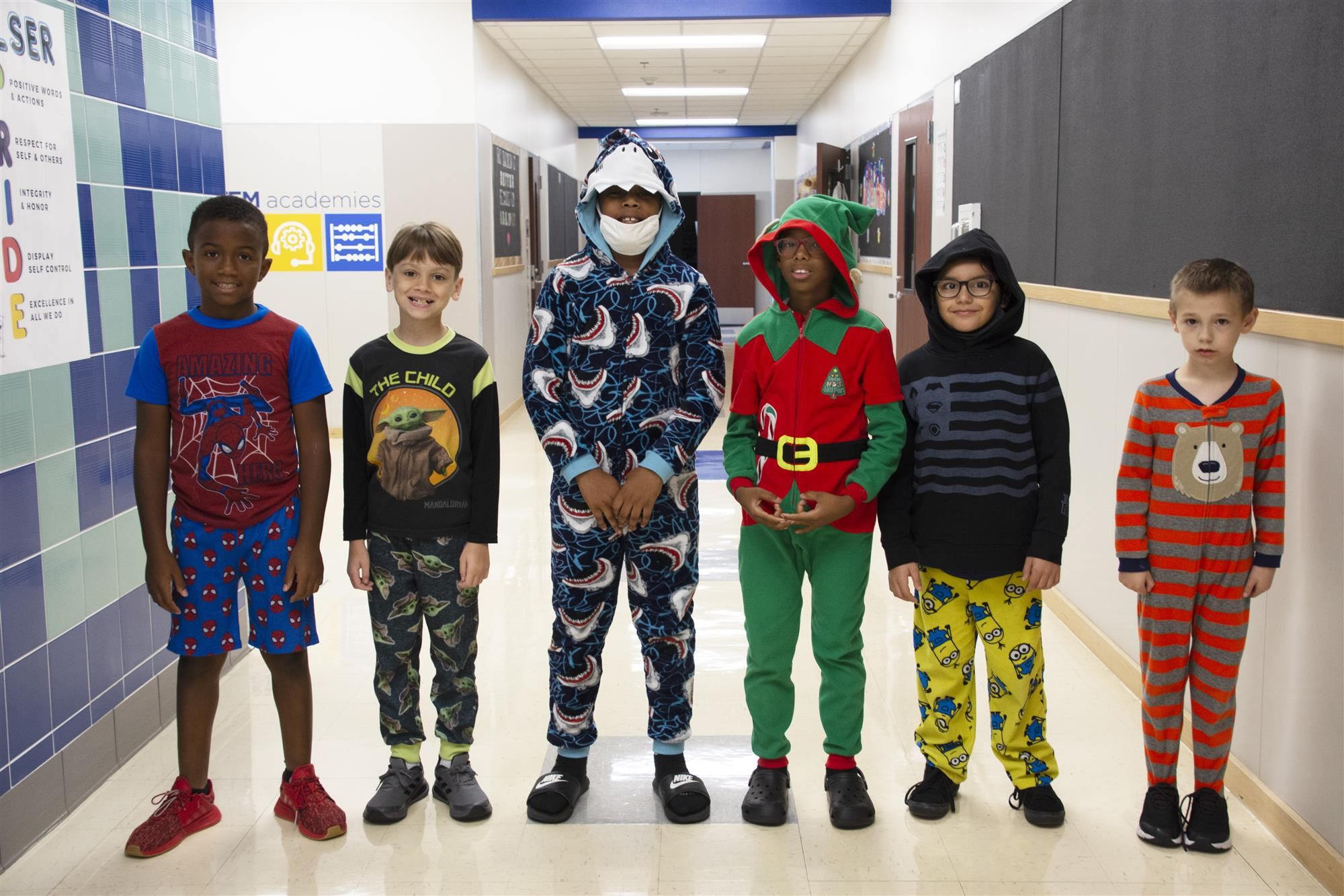 Students in pajamas stand in hallway