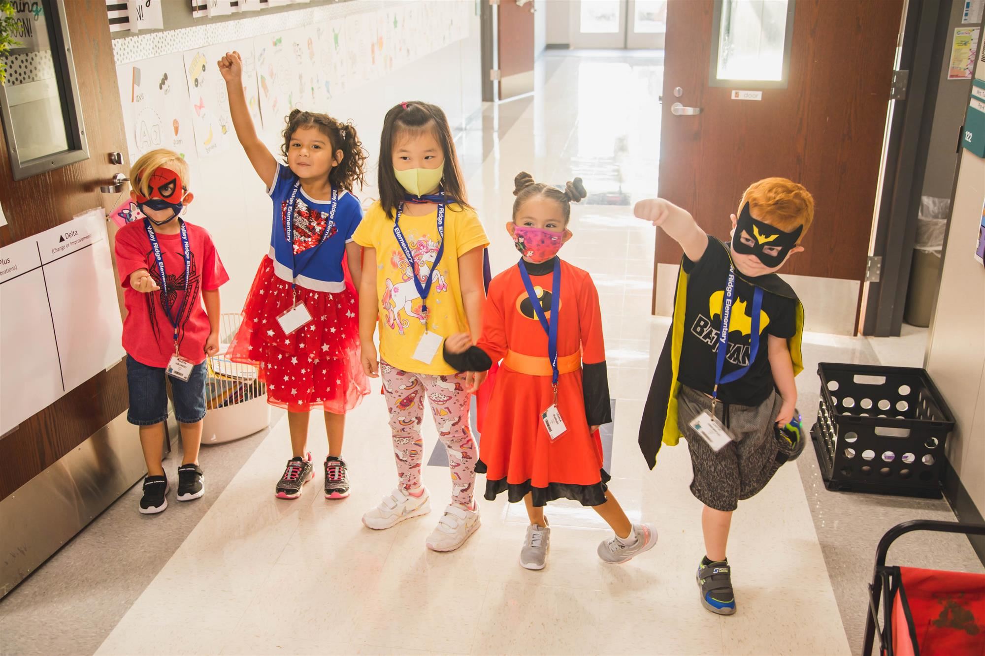 Students dressed in Superhero costumes stand in hallway