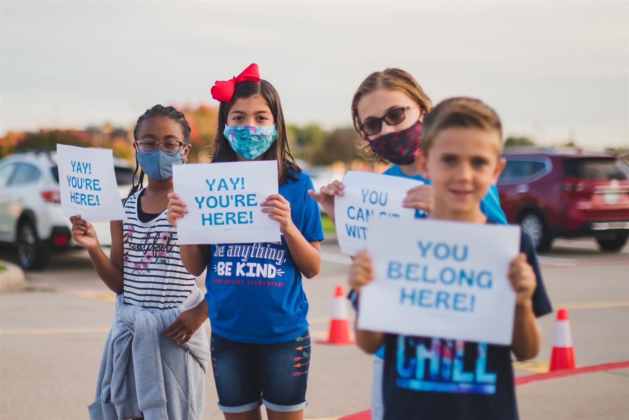 Students hold Kindness Week signs to greet others