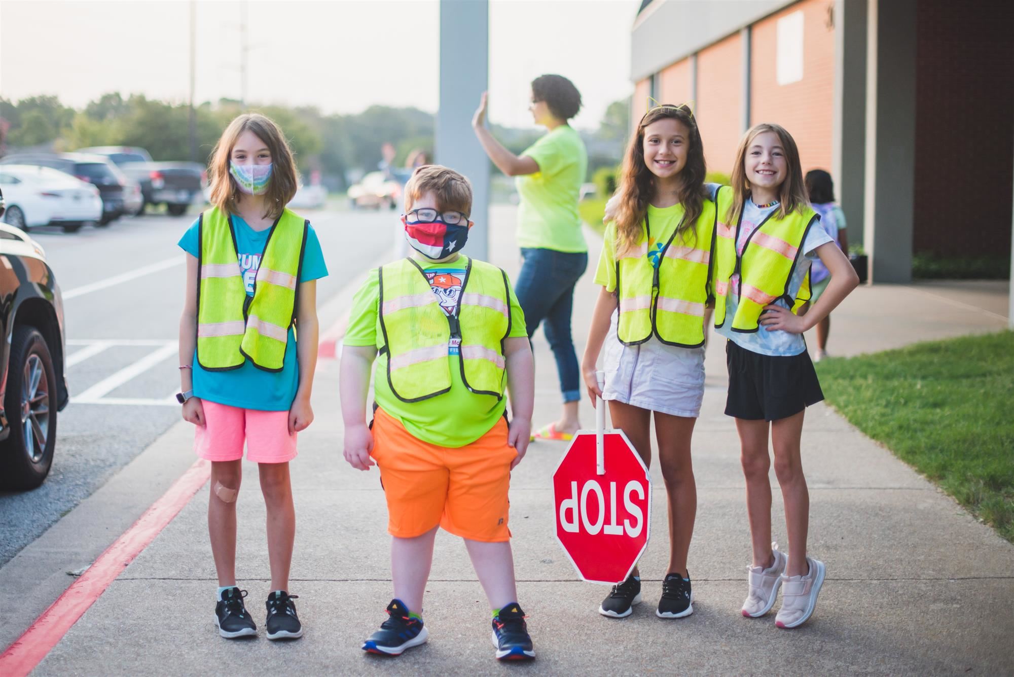 Students in neon vests stand outside of school