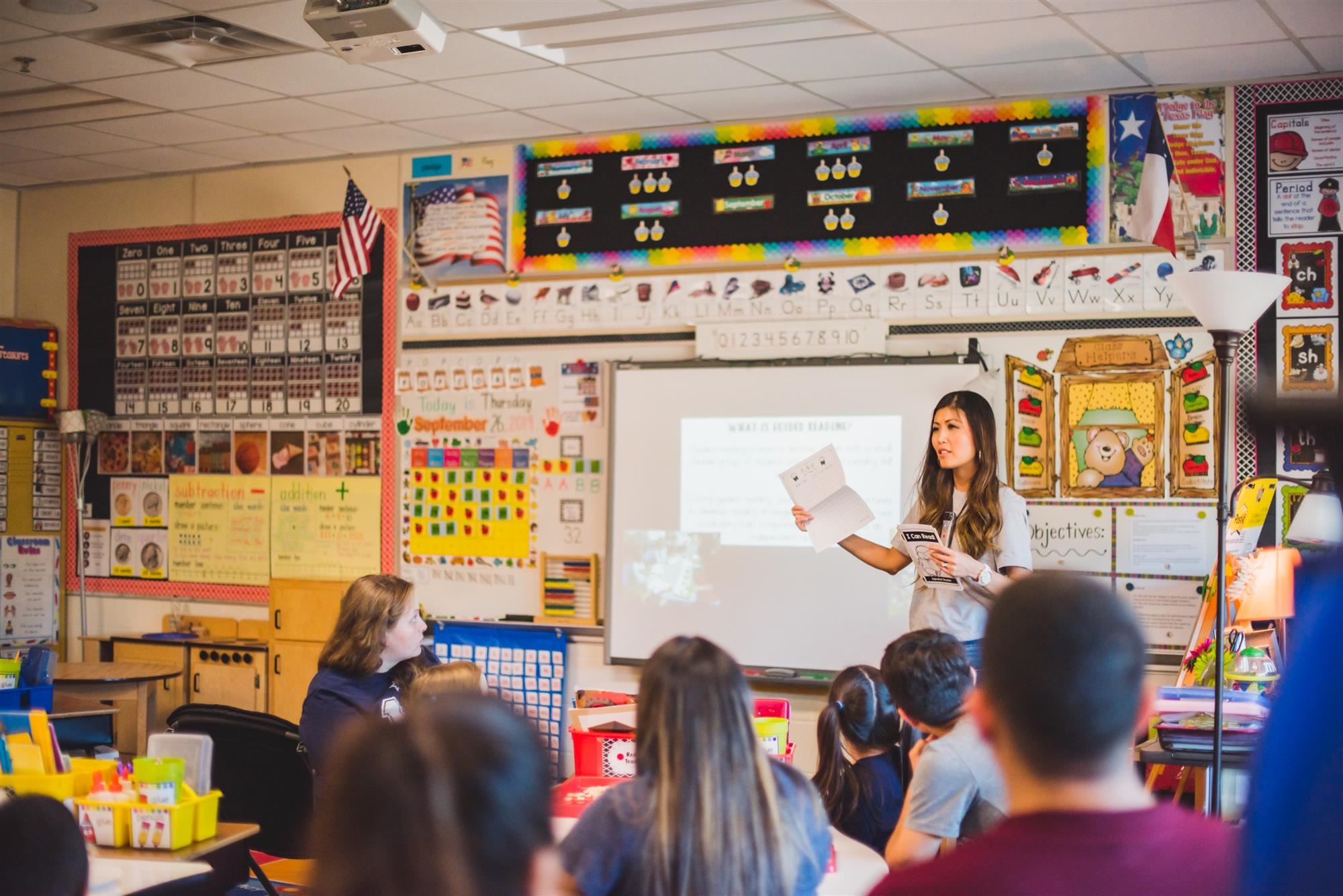 Teacher speaks to parents and students in classroom. 