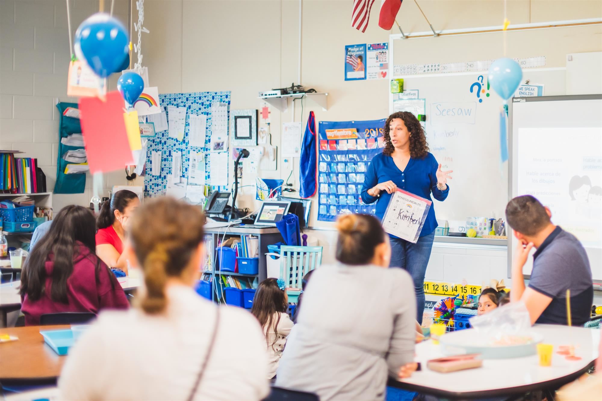 Teacher speaks to crowd of parents and students. 