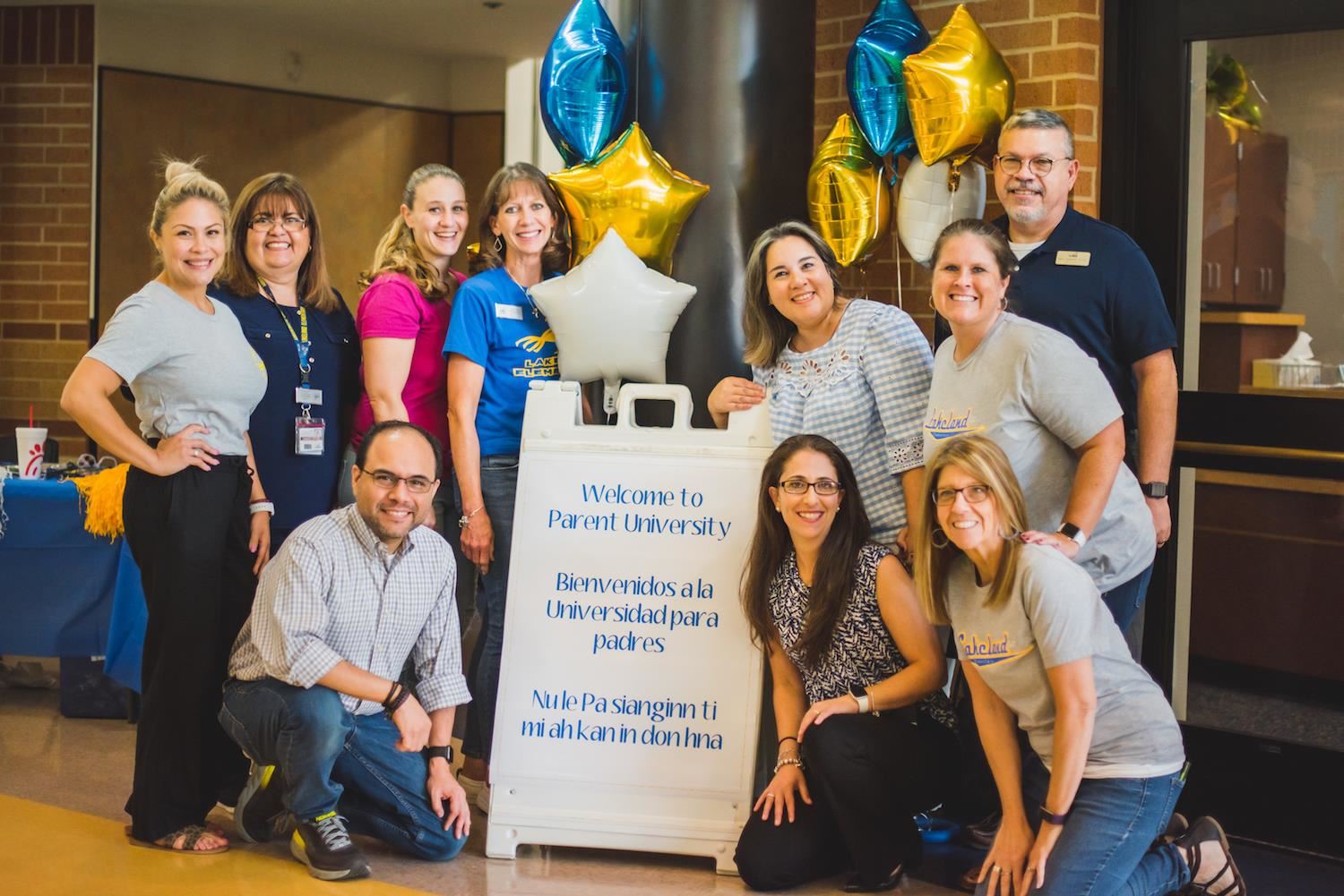 Lakeland staff pose for group photo in front of "Parent University" welcome sign. 