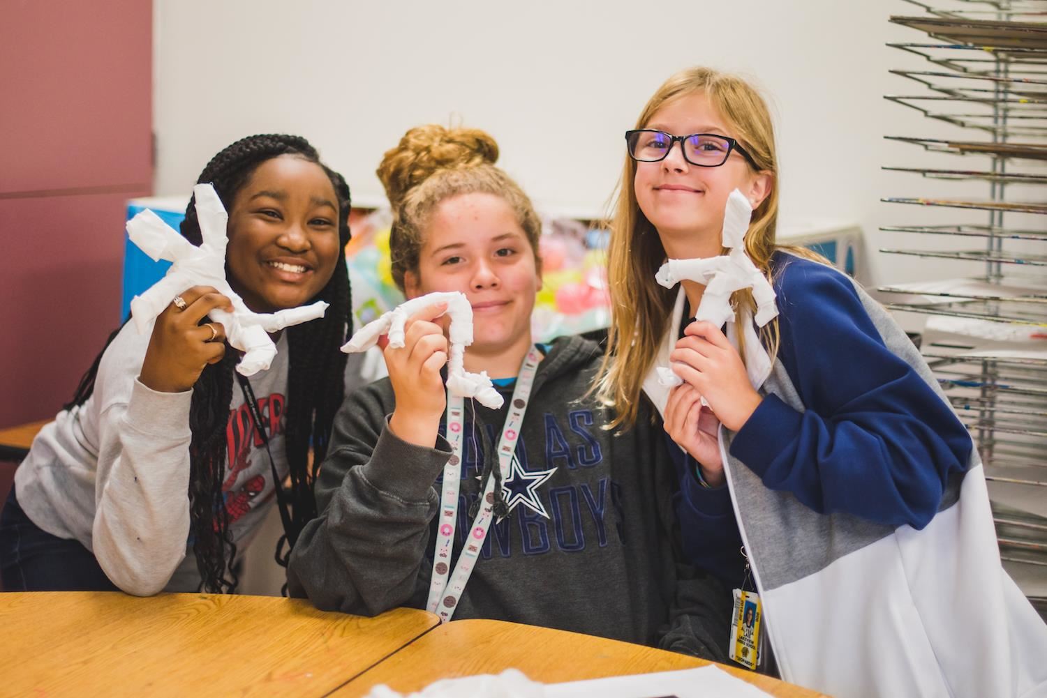 Students hold their handmade mummies 