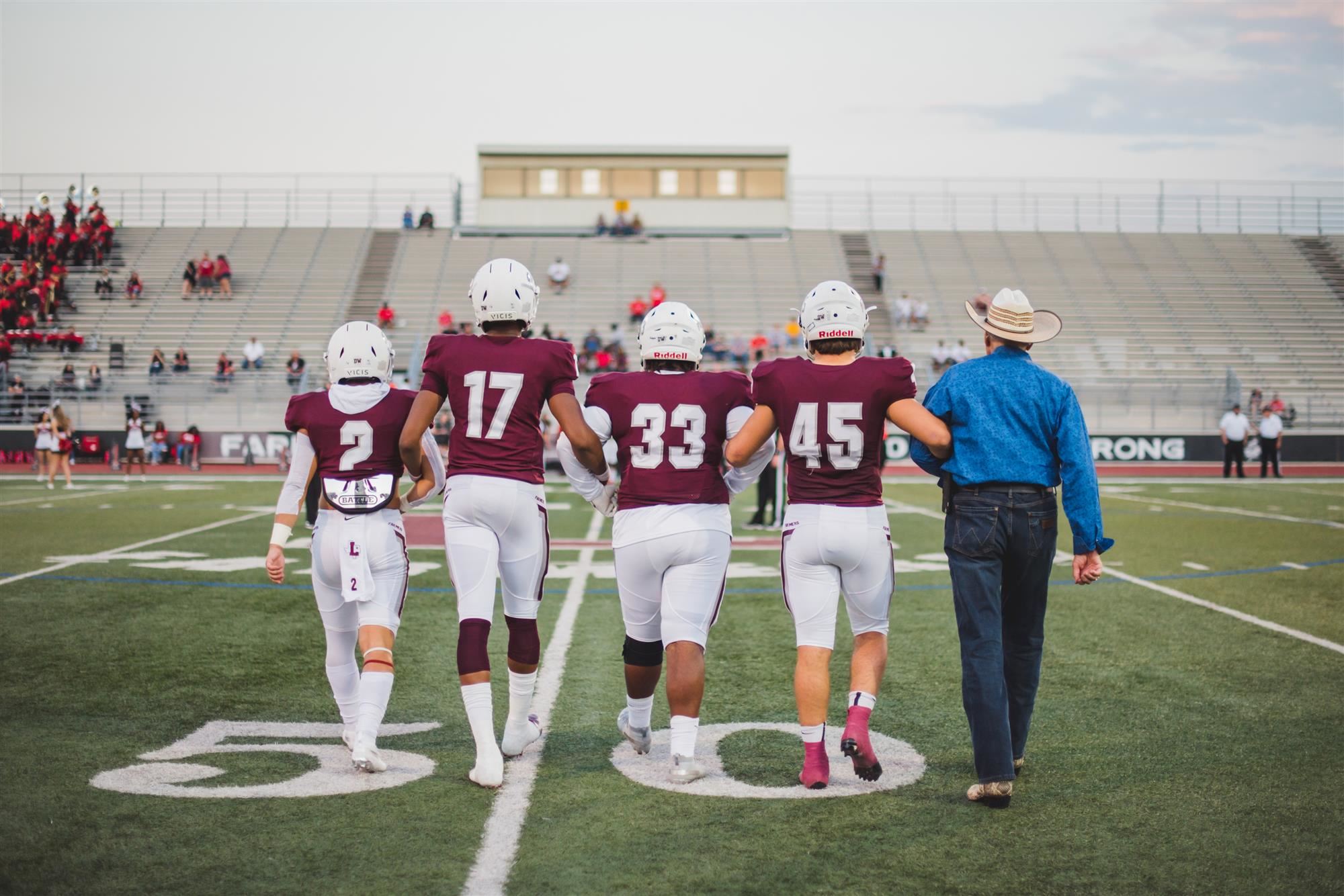 Football players and man walk to midfield 