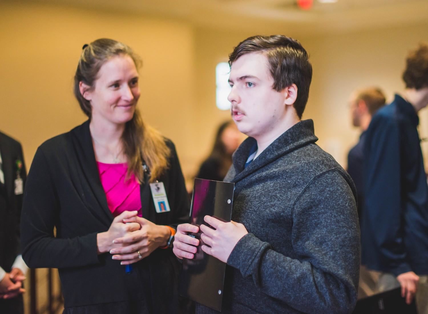 student and teacher talk to potential employee at job fair 