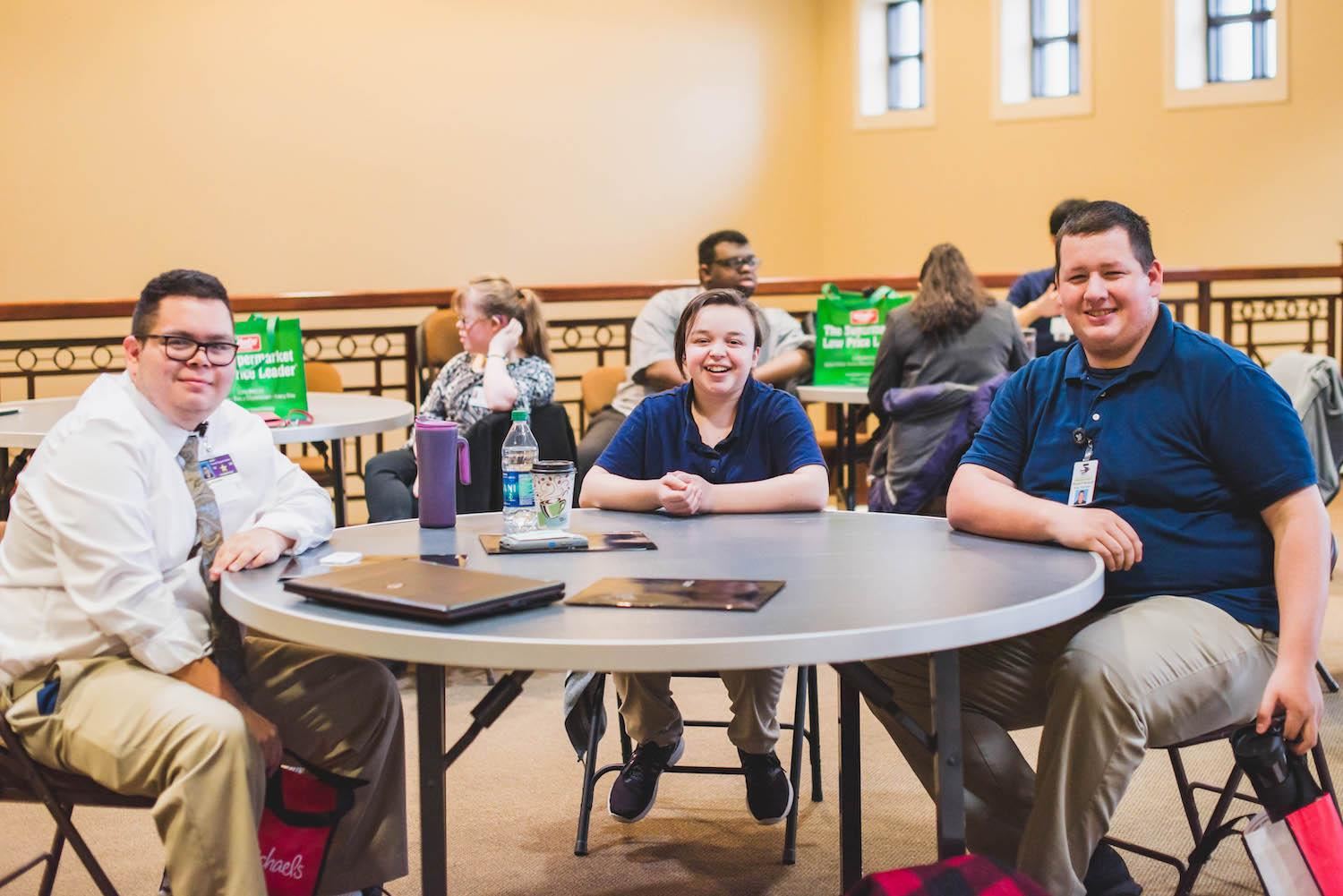 Group of three student smile around round table 