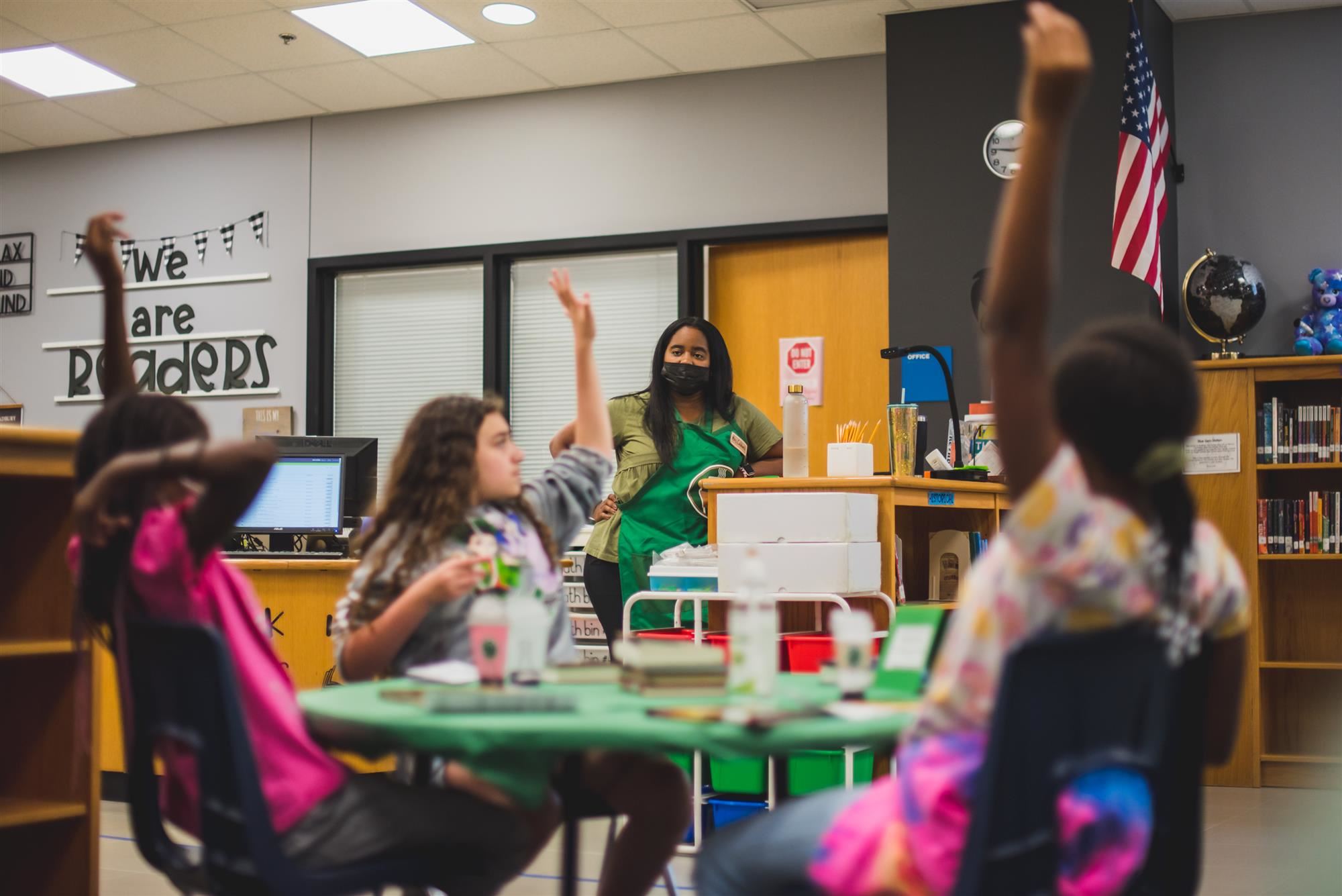 Students raise their hand to answer librarian's question