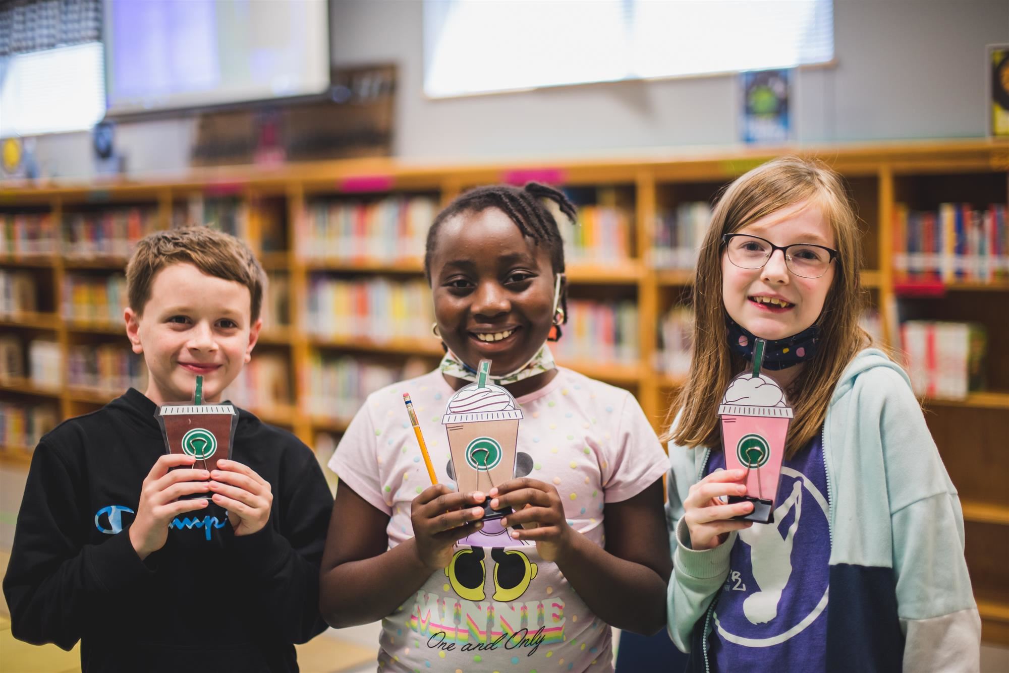 Students smile with paper "coffees"