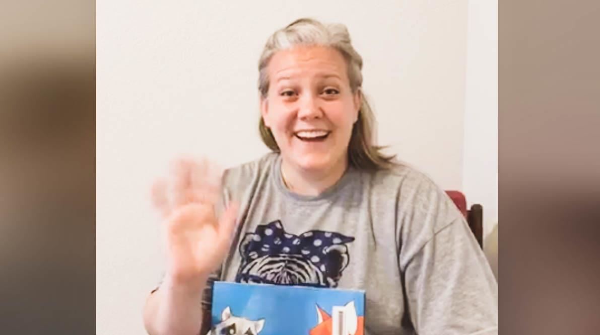 heather gronneberg waves to the camera with a book 