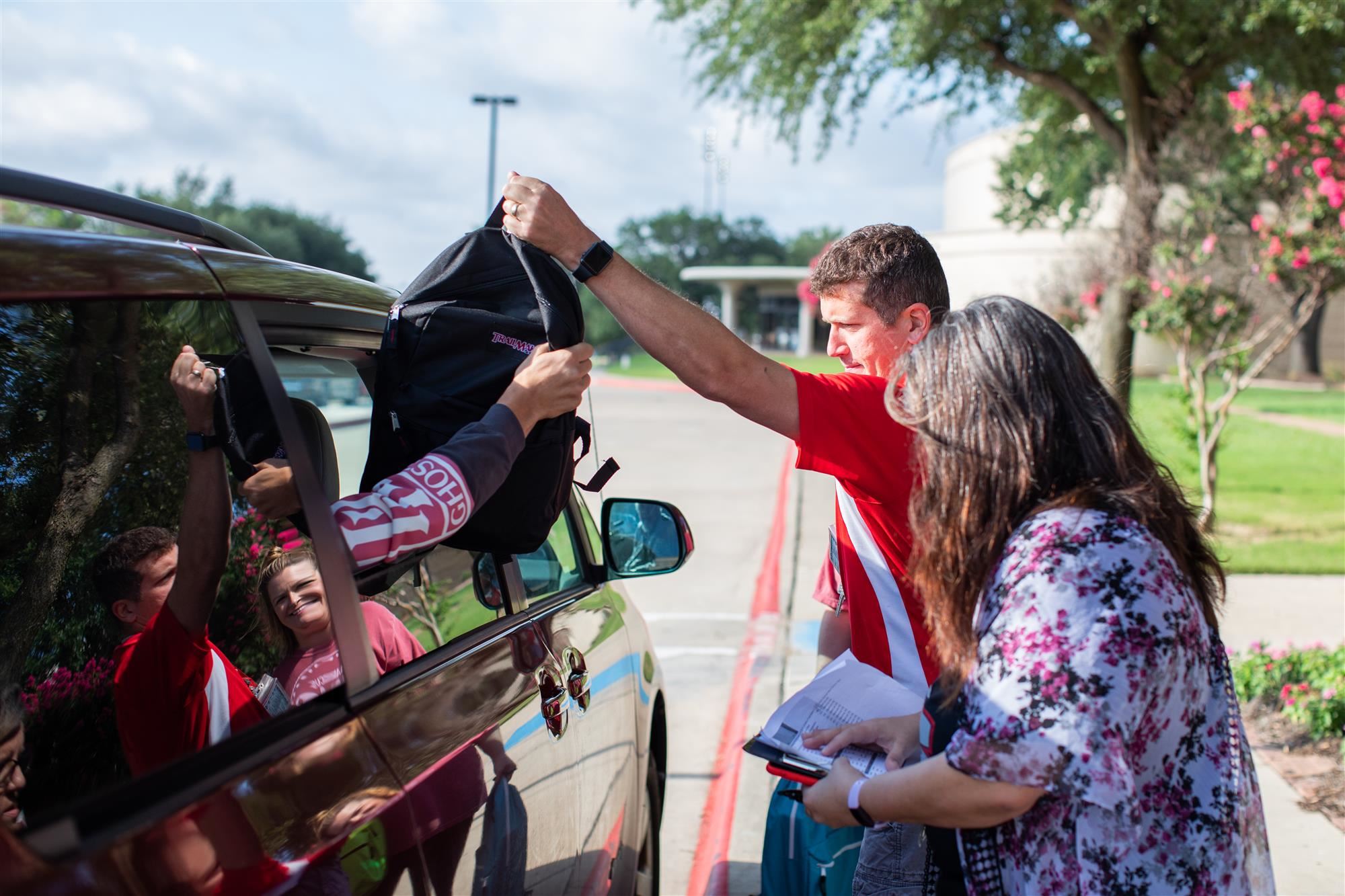 Volunteers hand out backpacks stuffed with supplies to families.